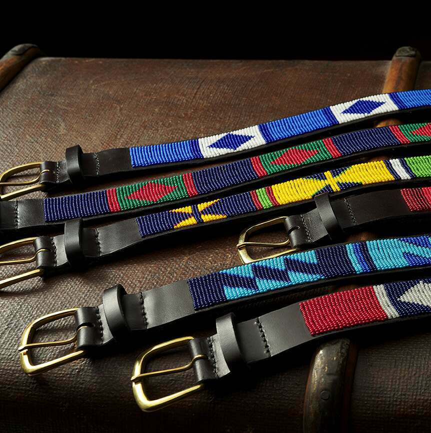 A Row of Cordings beaded belts laid out flat on a rustic 1920s trunk