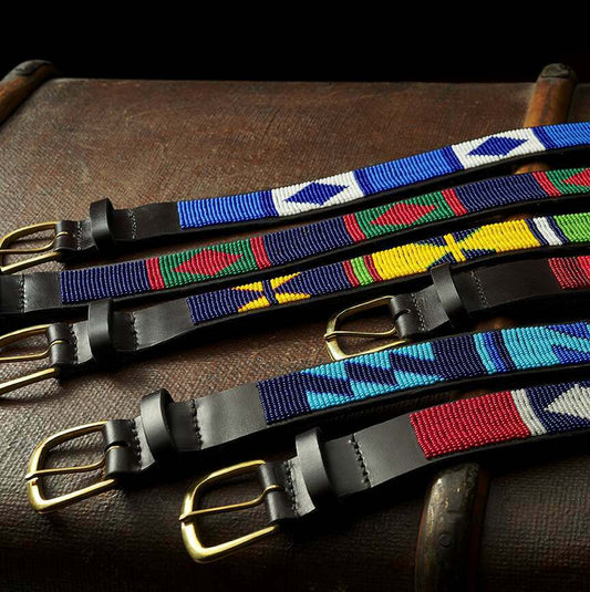 A Row of Cordings beaded belts laid out flat on a rustic 1920s trunk